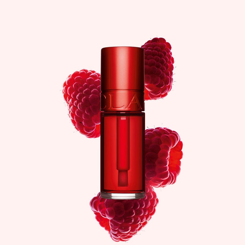ภาพถ่ายผลิตภัณฑ์ Clarins Red Water Lip Stain ในสี 03 วางอยู่ข้างราสเบอร์รี่บนพื้นหลังสีชมพูอ่อน