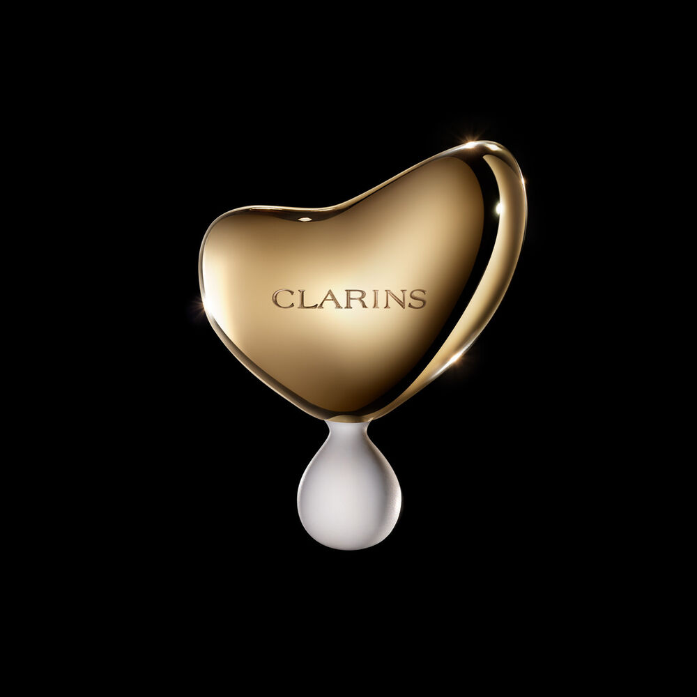 การถ่ายภาพของ Clarins Precious Massage Tool บนพื้นหลังสีเข้ม