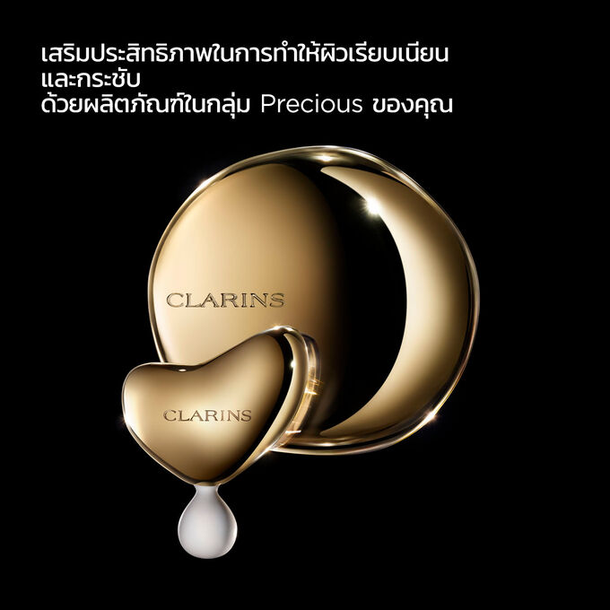 การถ่ายภาพของ Clarins Massage Tool บนพื้นหลังสีเข้มพร้อมข้อความที่เน้นเรื่องการใช้งานเพื่อเสริมประสิทธิภาพให้กับผลิตภัณฑ์ในกลุ่ม Precious