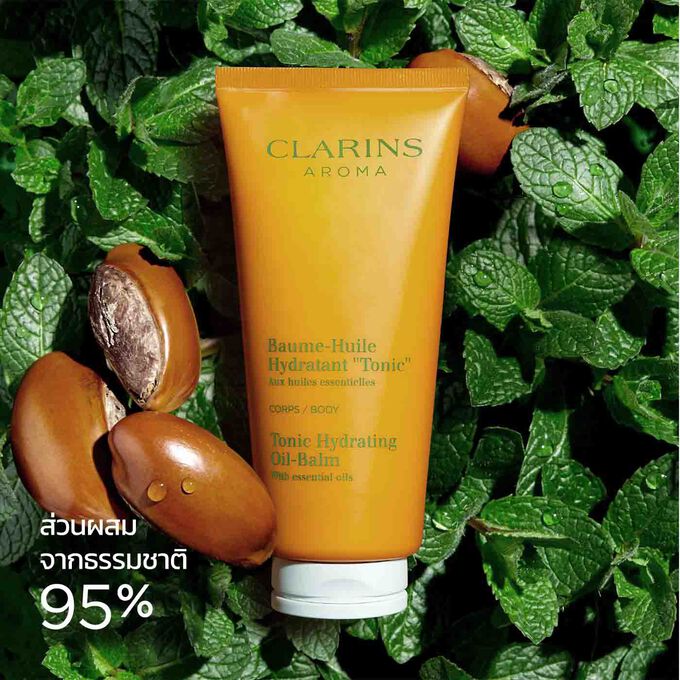 บรรจุภัณฑ์ของ Clarins Tonic Hydrating Oil-Balm ที่วางอยู่ท่ามกลางใบมิ้นต์และเมล็ดเชีย เพื่อเน้นถึงต้นกำเนิดจากธรรมชาติของส่วนผสม