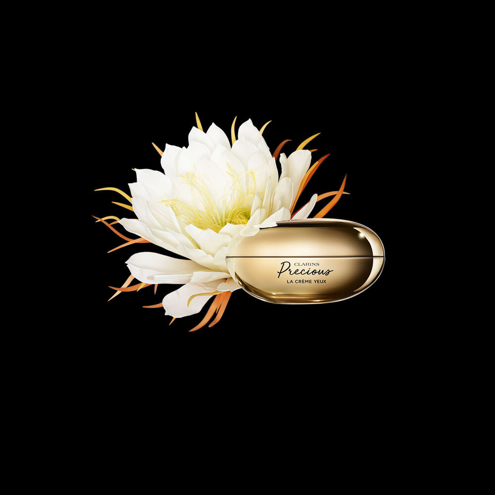 ภาพผลิตภัณฑ์ Clarins Precious Eyes ครีมบำรุงรอบดวงตาที่วางใกล้กับดอกมูนไลท์บนพื้นหลังสีเข้ม
