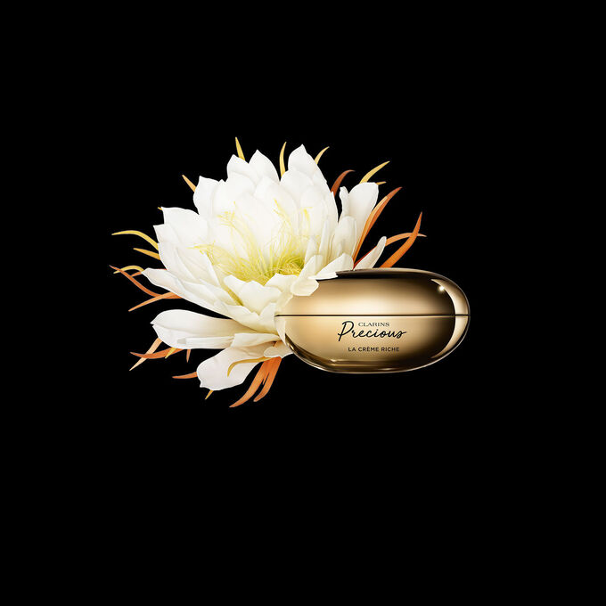 ภาพผลิตภัณฑ์ Clarins Precious Rich Cream ที่วางใกล้กับดอกมูนไลท์บนพื้นหลังสีเข้ม