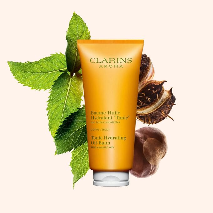 ภาพผลิตภัณฑ์ของบรรจุภัณฑ์ Clarins Tonic Hydrating Oil-Balm ที่วางใกล้ใบมิ้นต์และเมล็ดเชีย บนพื้นหลังสีพีช