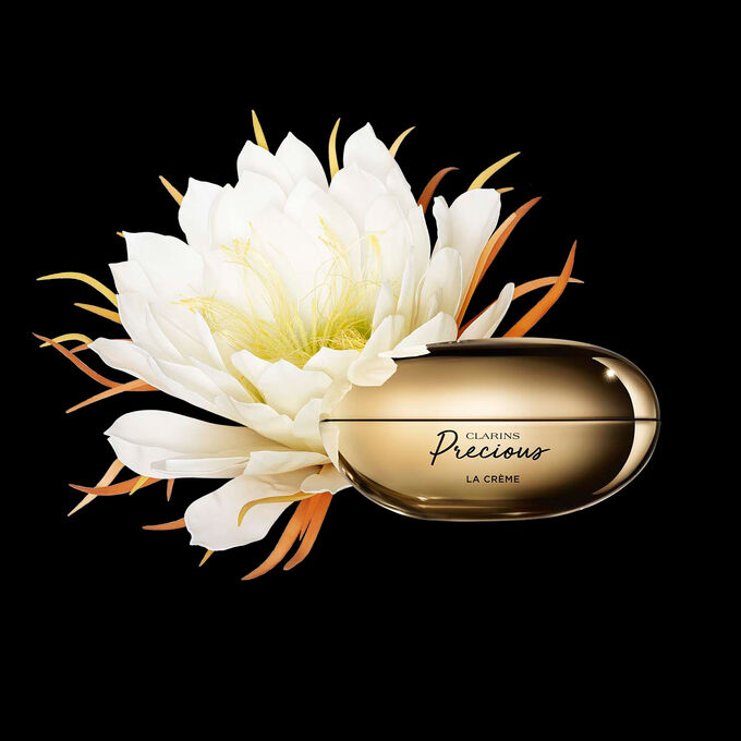 ภาพผลิตภัณฑ์ Clarins Precious Soft Cream ที่ถูกวางอยู่ใกล้กับดอกมูนไลท์บนพื้นหลังสีเข้ม