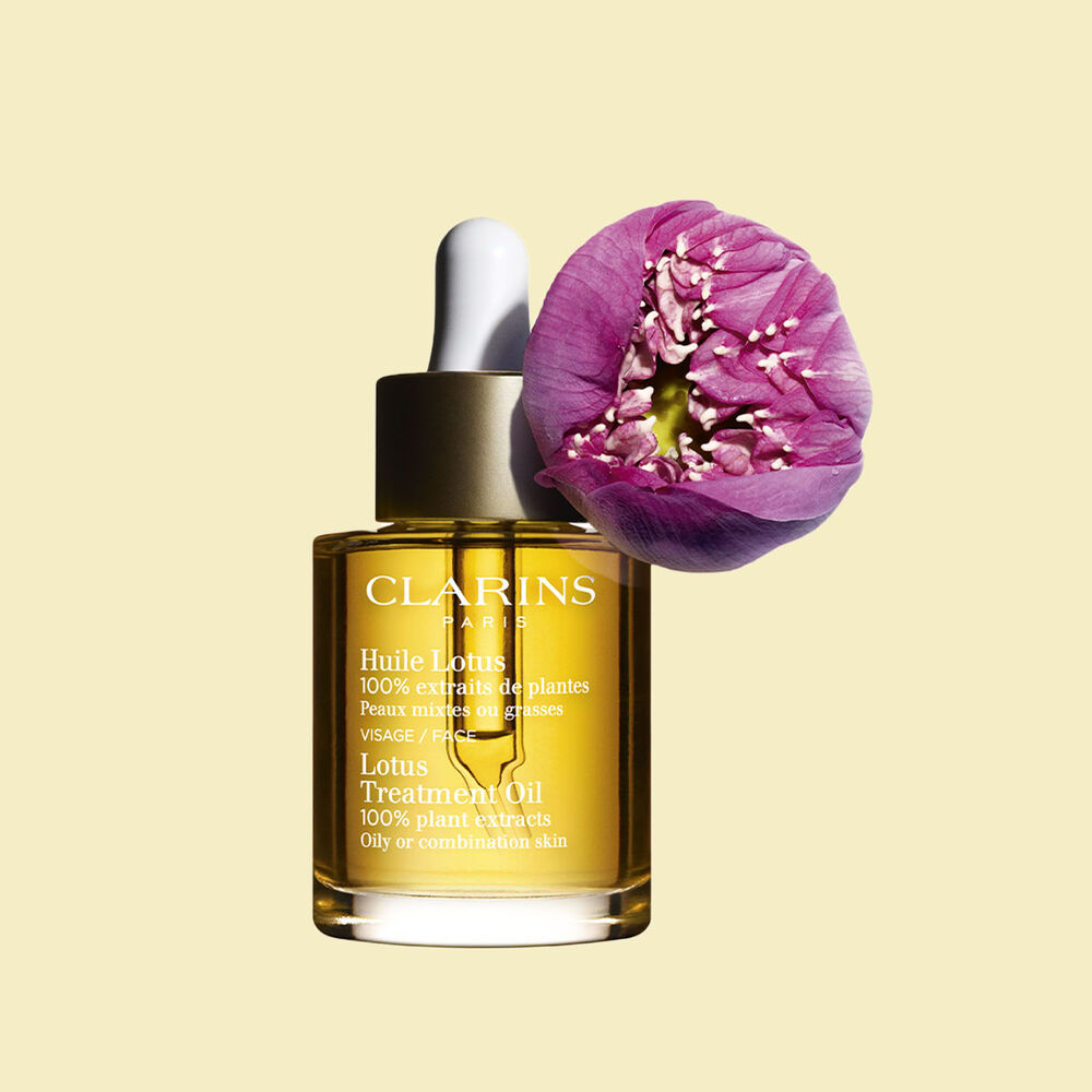 ภาพผลิตภัณฑ์ของขวด Clarins Lotus Face Treatment Oil ที่วางอยู่ใกล้ดอกบัว บนพื้นหลังสีเหลืองอ่อน